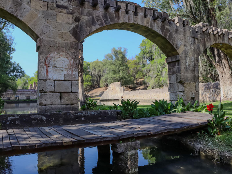 Antiguo puente de piedra rodeado de lagunas y vegetación en el Bosque de las Truchas.